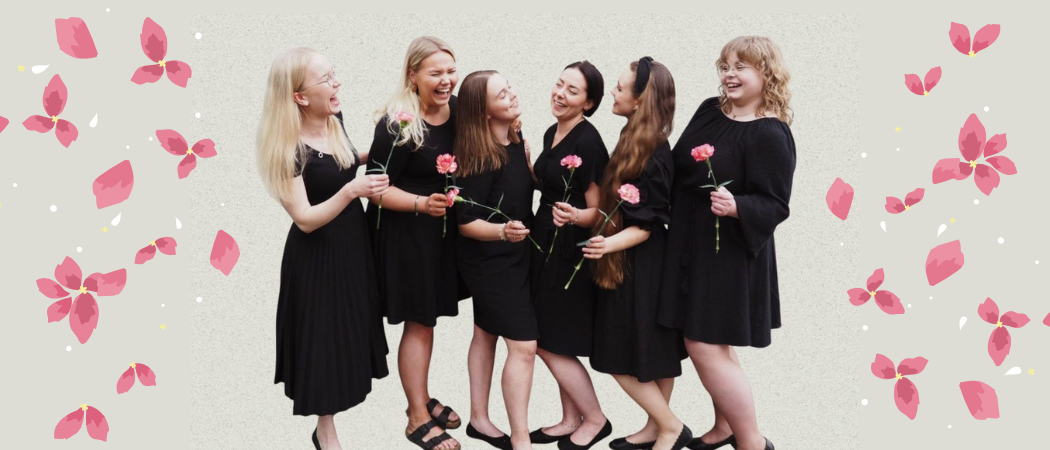 Lauluyhtye Fridan laulajat tummissa mekoissa vaaleanpunaiset neilikat k&auml;siss&auml;&auml;n.