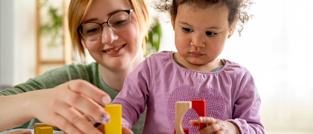Äiti ja lapsi rakentavat yhdessä puupalikoilla.