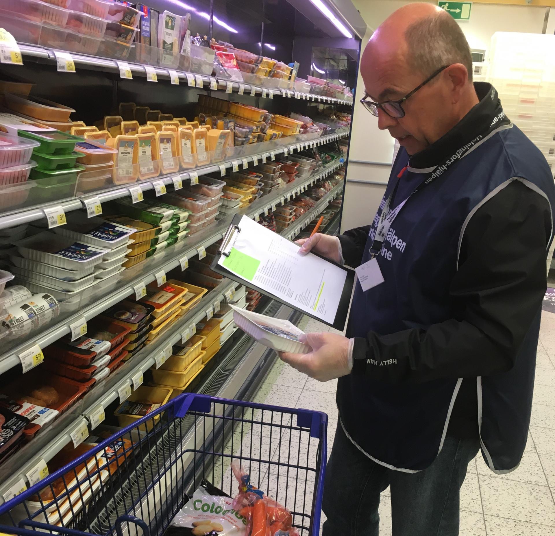 Helsinki-avun vapaaehtoinen Lasse Björses kaupassa keräämässä ostoksia
