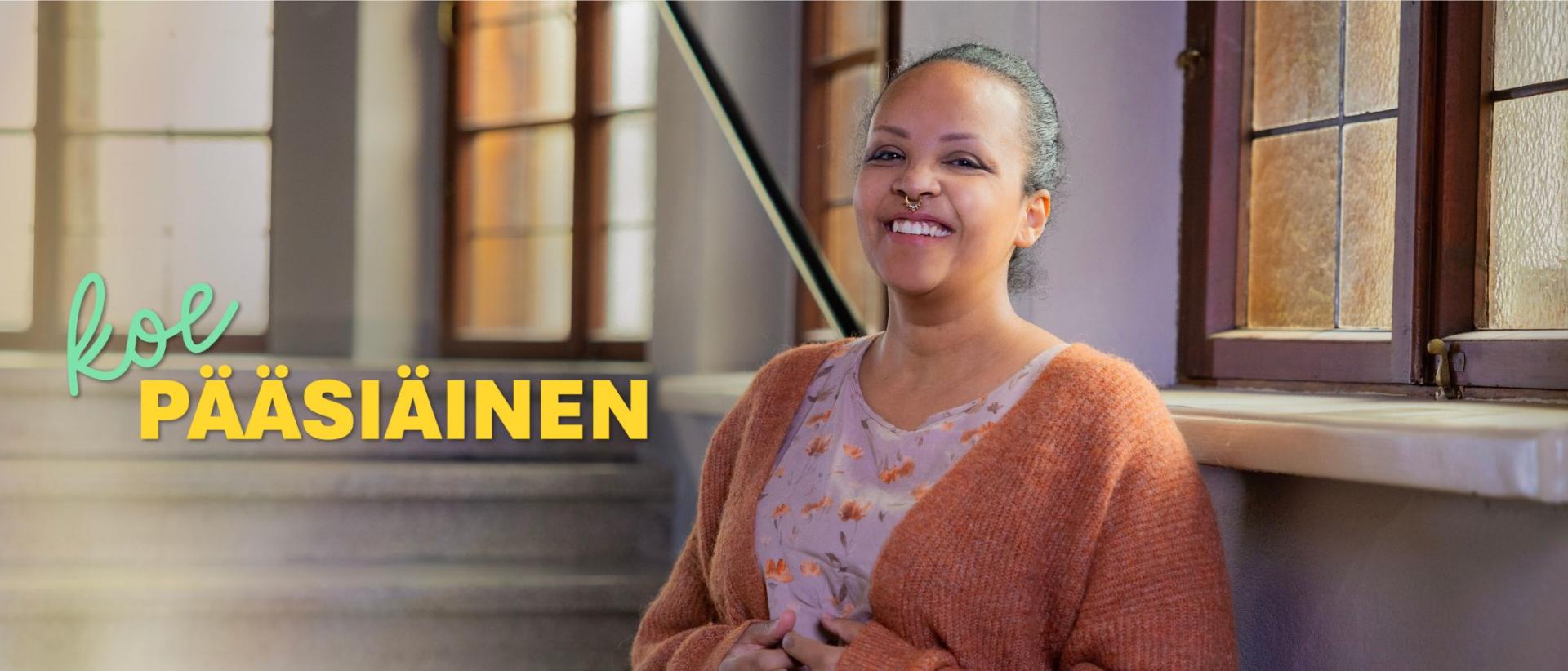 Nainen ruskeassa villatakissa, taustalla kirkon sisäportaat
