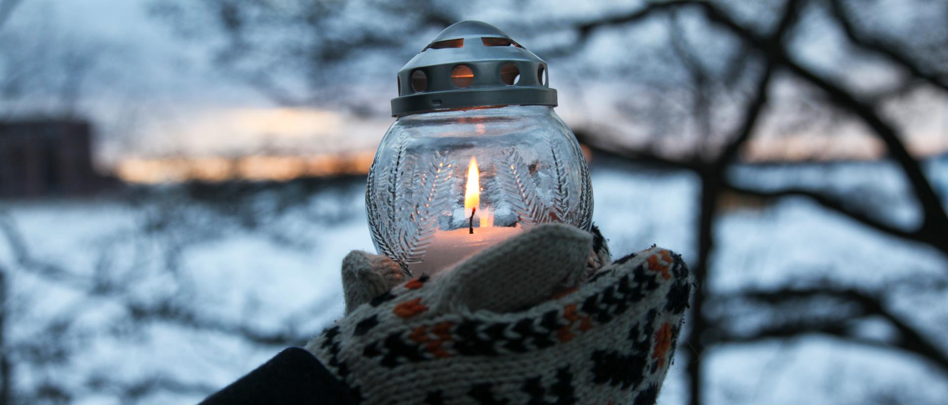Hautakynttilä käsissä, taustalla talvinen maisema