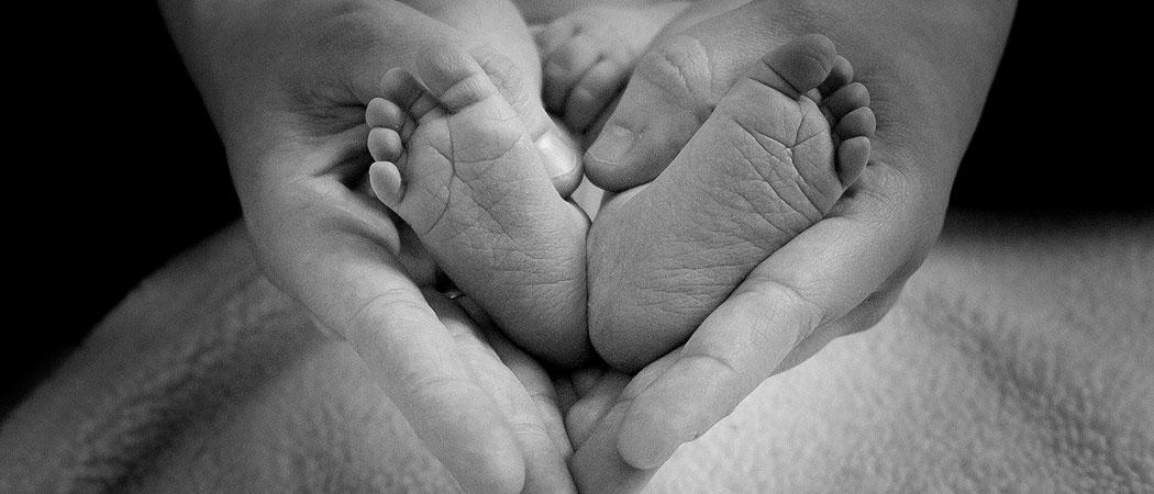 Kuvassa vauvan jalat äidin käsien välissä