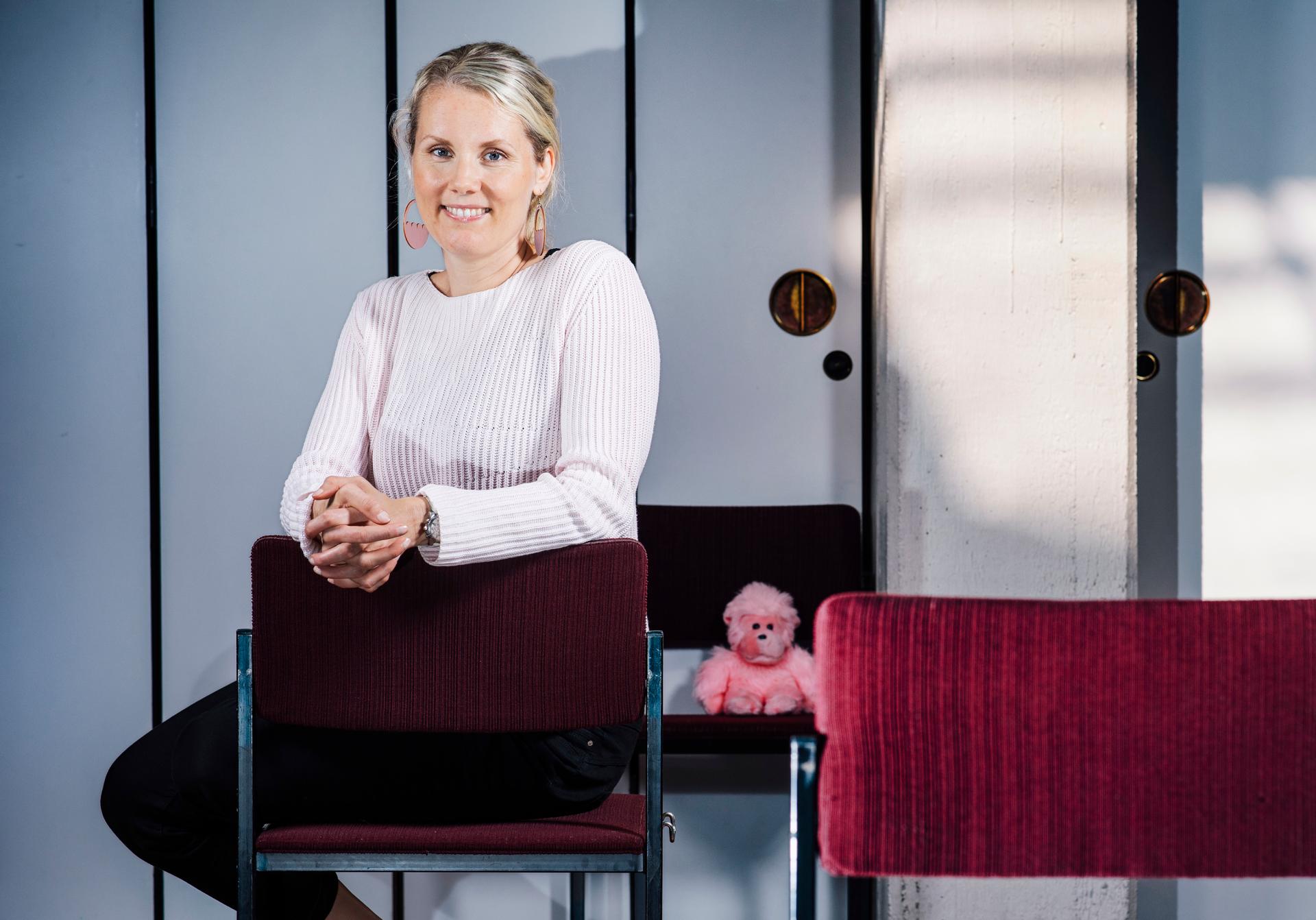 Satu Ketonen istuu Oulunkylän kirkkosalissa, takapenkistä kurkistaa vaaleanpunainen leikkiapina