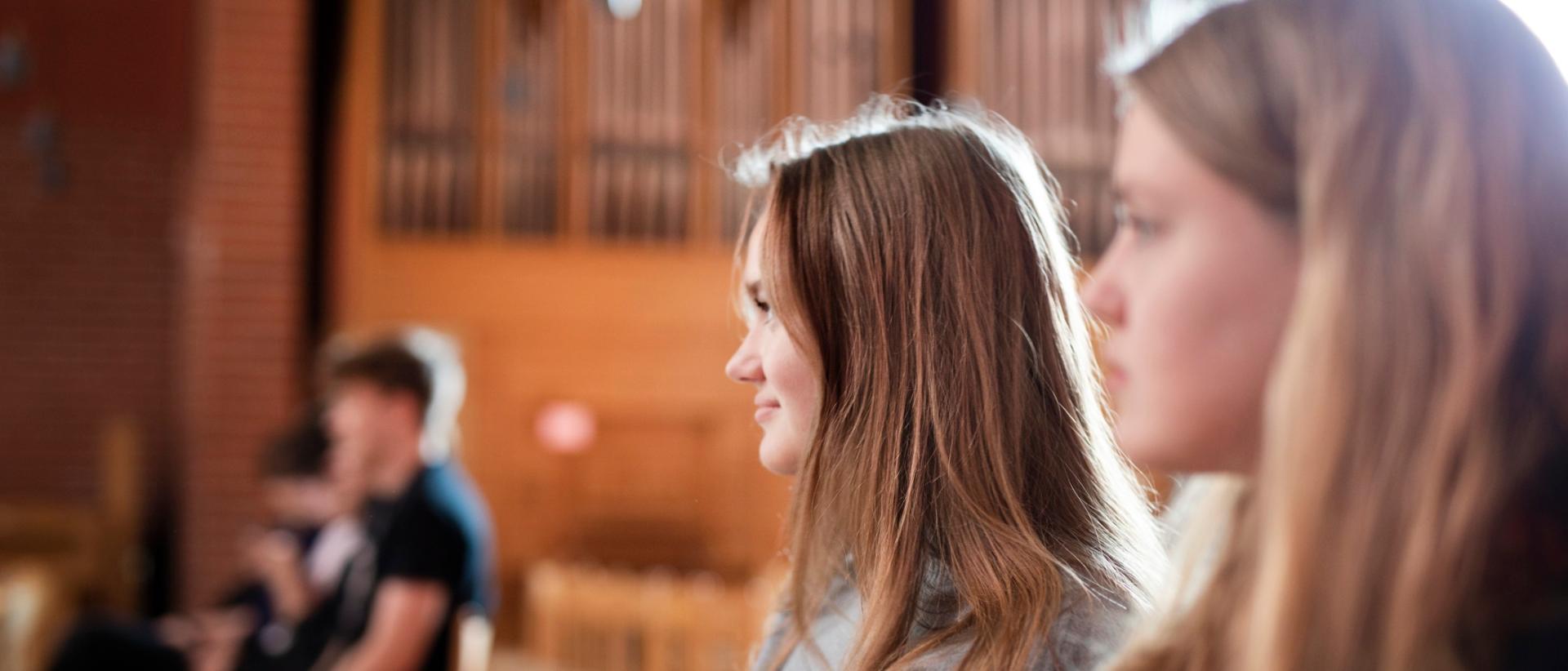 Nuoria istuvat kirkossa, taustalla urut.