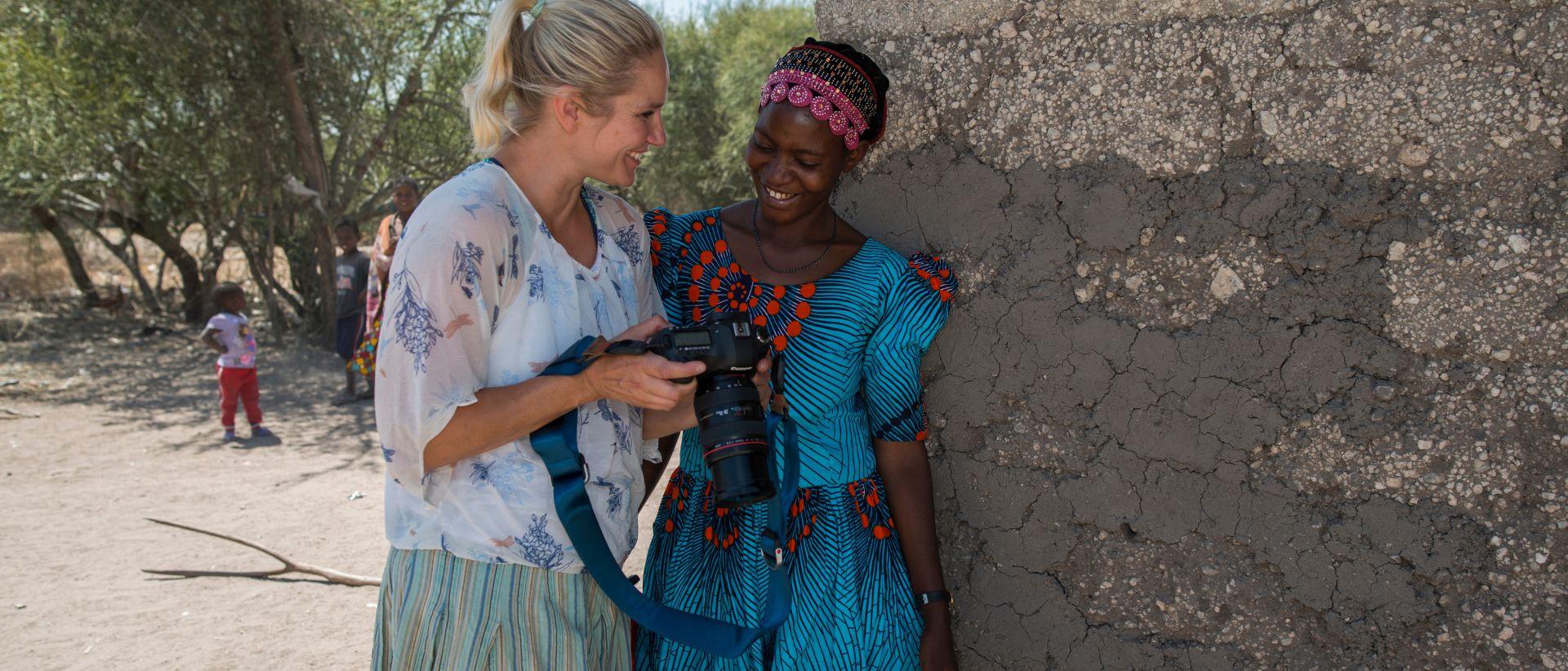 Laura Malmivaara ja kuvattava nainen katsovat kameran kuvia hymyillen.