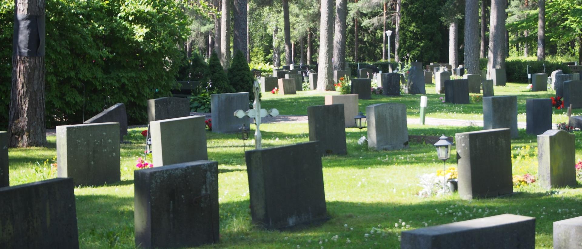 Kesäinen näkymä hautausmaalle, etualalla hautakiviä ja taustalla mäntyjä
