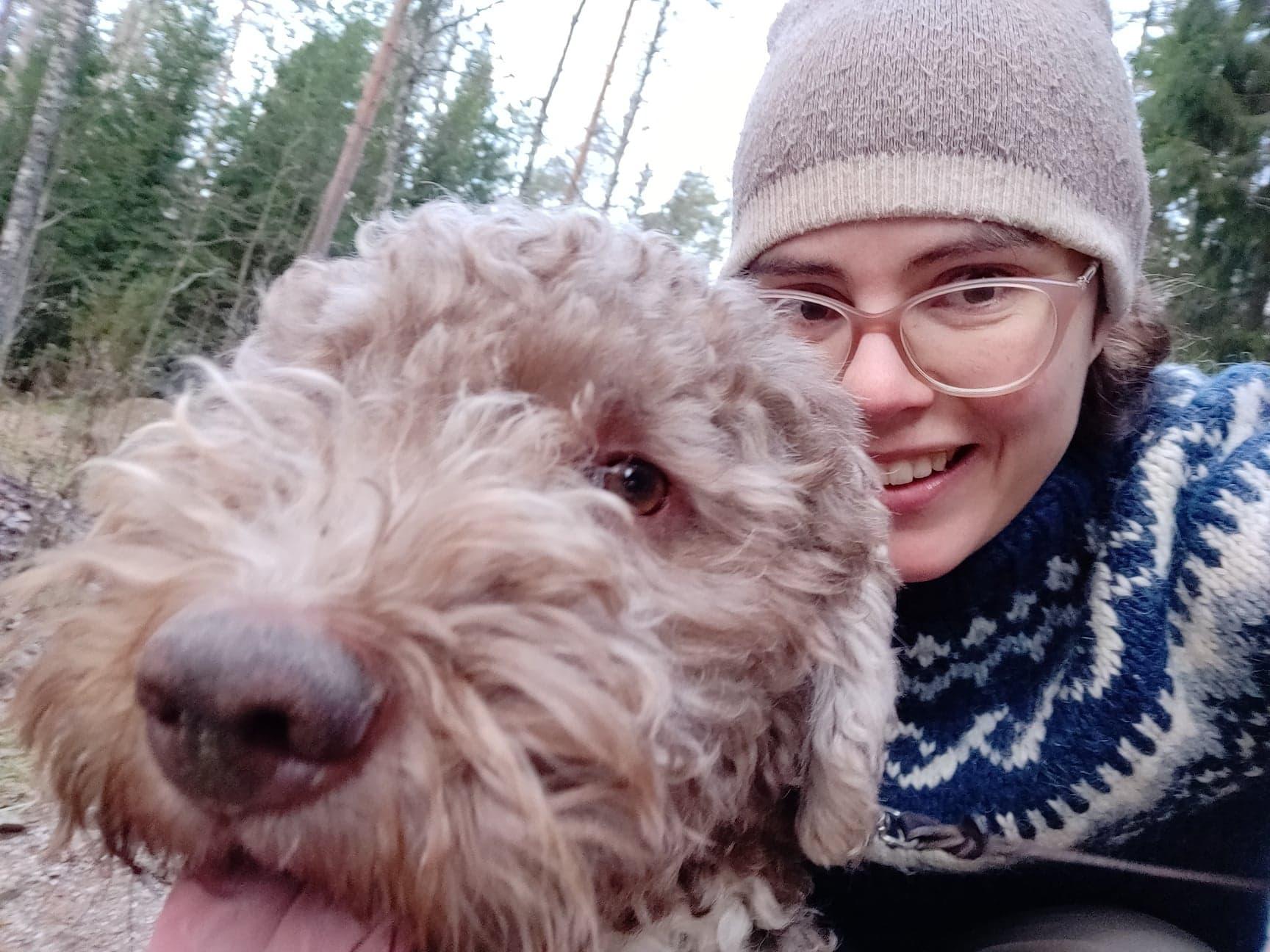 En hundägare busar med sin hund i skogen.