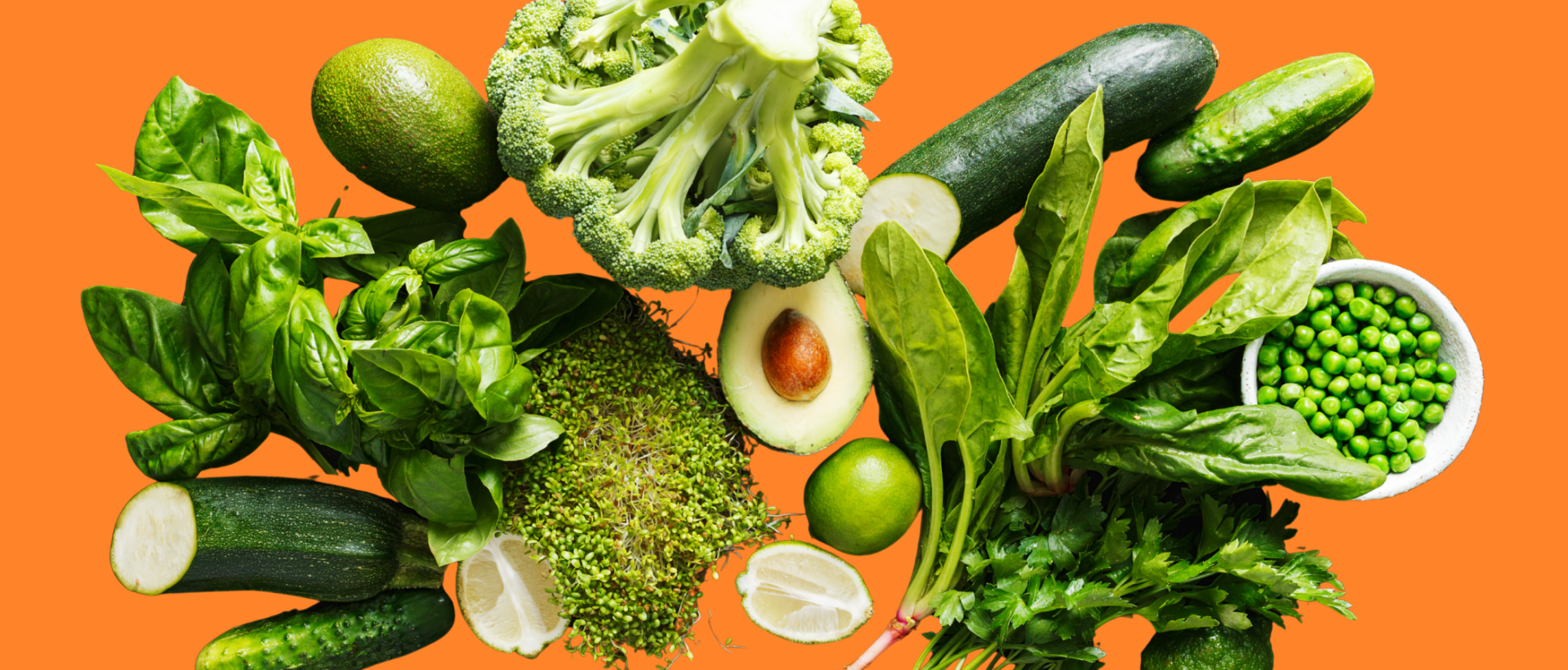Green vegetables and fruits on an orange background.