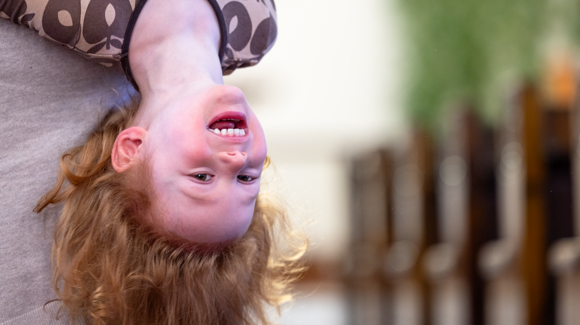 En liten pojke busar och hänger upp och ner så att håret hänger i golvet.