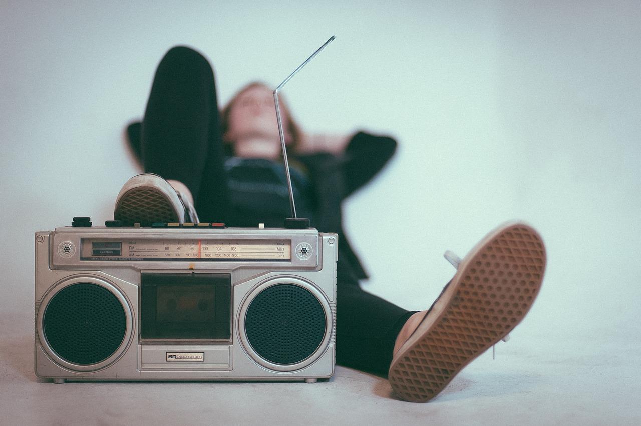 Tyttö makoilemassa ja nojaa jalkaa vanhaan radioon.