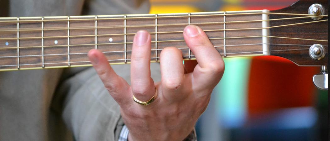 Miehen käsi kitaran kaulalla