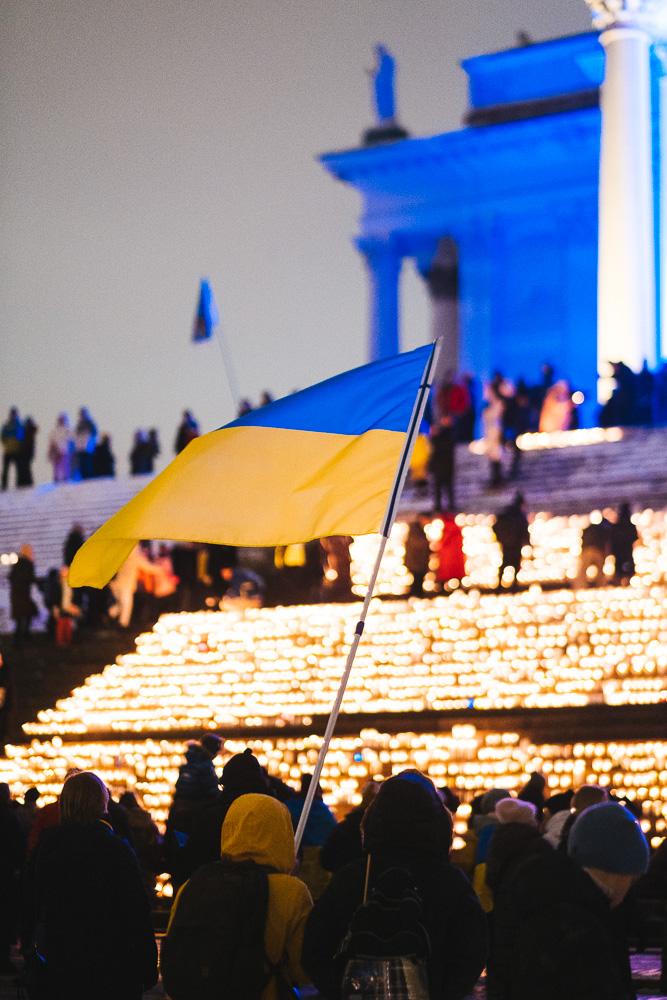 Paljon kynttilöitä Tuomiokirkon portailla pimenevässä illassa ja liehuva Ukrainan lippu.